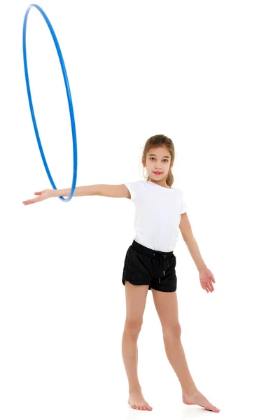 Una niña con una camiseta blanca realiza ejercicios con un aro. — Foto de Stock