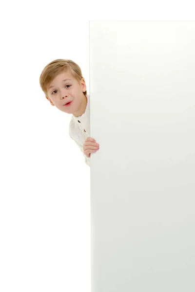Mały chłopiec jest patrząc zza pusty transparent. — Zdjęcie stockowe