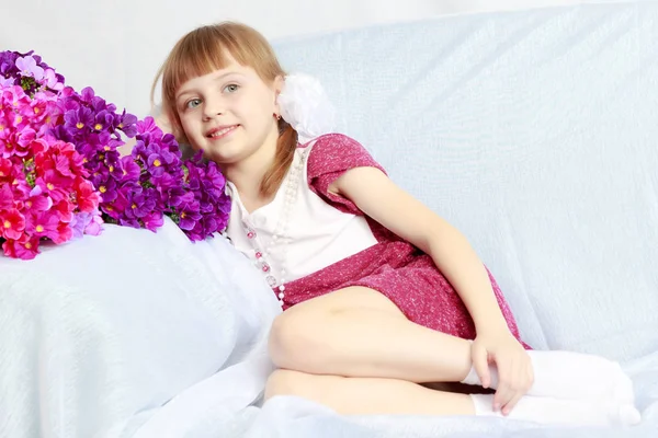 Fille s'assoit à côté d'un bouquet de fleurs . — Photo