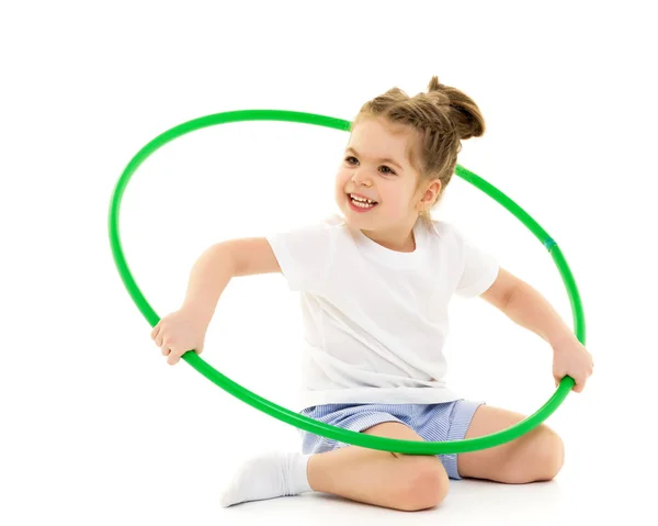 Beyaz tişörtlü küçük bir kız çemberle egzersiz yapıyor.. — Stok fotoğraf