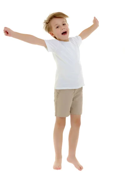 En liten pojke i en ren vit T-shirt hoppande roligt. Stockbild