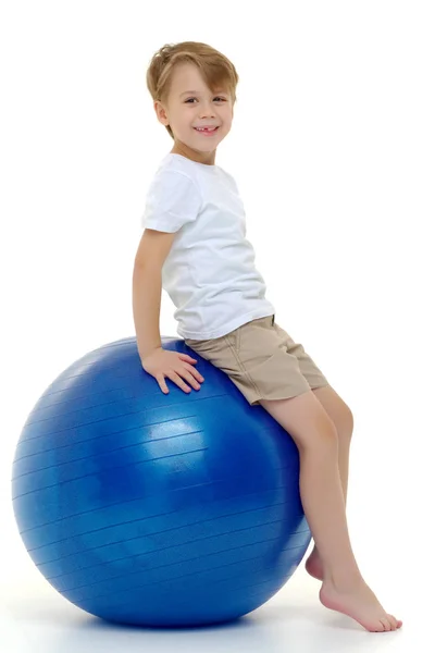 大きなボールに小さな男の子は、フィットネスに取り組んでいます。白い T シャツ — ストック写真