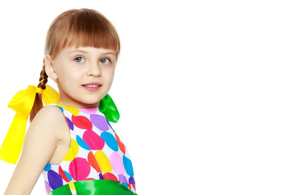 Ein kleines Mädchen in einem Kleid mit einem Muster aus buntem Zirkel — Stockfoto