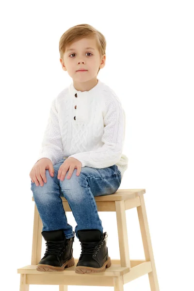 Malý chlapec sedí na židli. — Stock fotografie