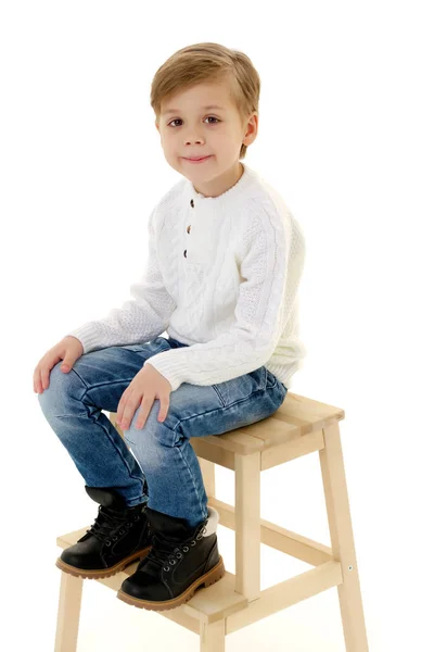 En liten pojke sitter på en stol. — Stockfoto