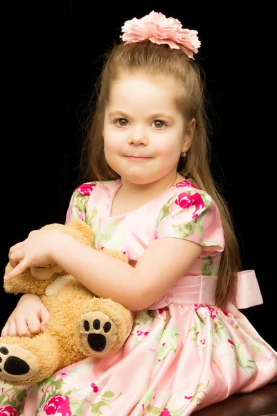 Niña con un osito de peluche sobre un fondo negro. —  Fotos de Stock