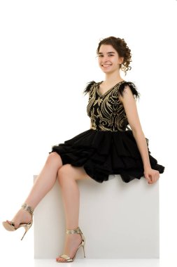 Genç kız beyaz bir küp üzerinde stüdyo poz.