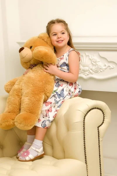 在沙发上抱着泰迪熊的小女孩. — 图库照片