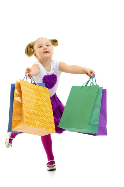 Dziewczynka z wielobarwnymi torbami w rękach. — Zdjęcie stockowe