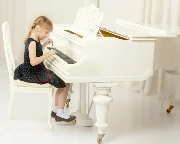 Schönes kleines Mädchen spielt auf einem weißen Flügel. — Stockfoto