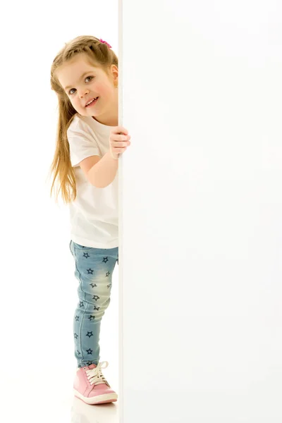 A little girl is looking from behind an empty banner. — Stock Photo, Image