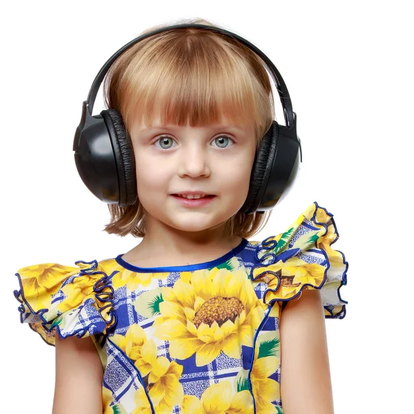 Une petite fille avec écouteurs écoutant de la musique. — Photo
