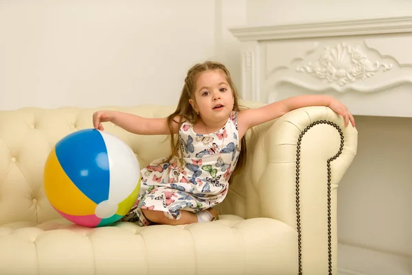 Menina com uma bola no sofá . — Fotografia de Stock