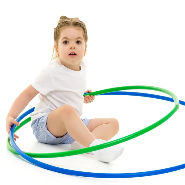 Una bambina in una t-shirt bianca esegue esercizi con un cerchio. — Foto Stock