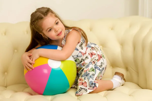 ソファの上にボールを持つ小さな女の子. — ストック写真