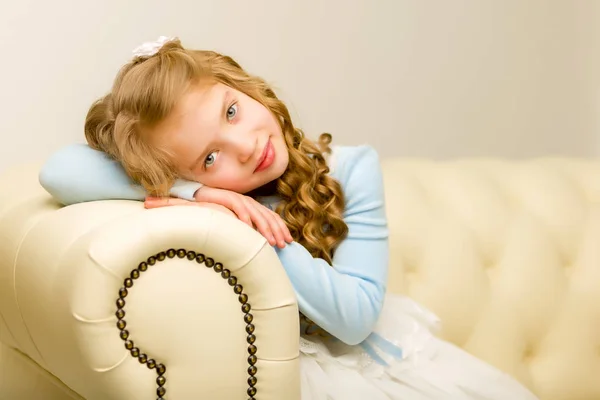 A menina está sentada no sofá — Fotografia de Stock