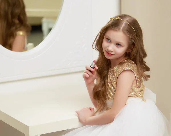 A little girl near the mirror paints lipstick lips — Stock Photo, Image