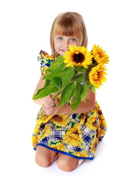 Kleines Mädchen mit Sonnenblumenblüten. — Stockfoto