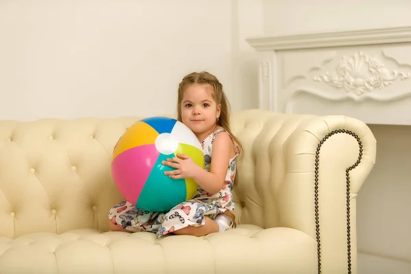 Klein meisje met een bal op de Bank. — Stockfoto