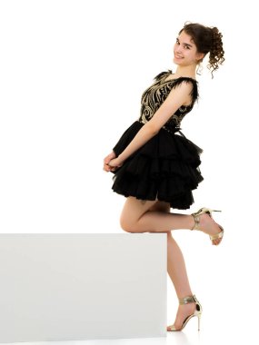 Genç kız beyaz bir küp üzerinde stüdyo poz.