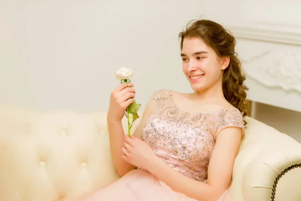 Adolescente sentada no sofá segurando uma flor na mão . — Fotografia de Stock