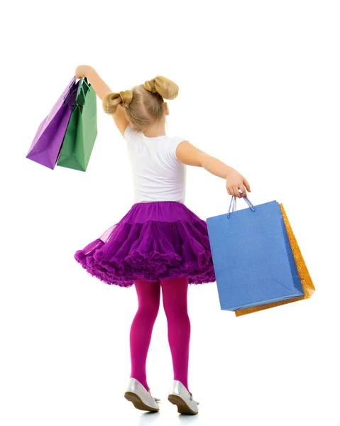 Klein meisje met multi-gekleurde tassen in hun handen. — Stockfoto