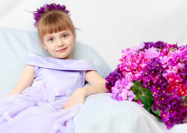 Kız bir buket çiçek yanında oturuyor.