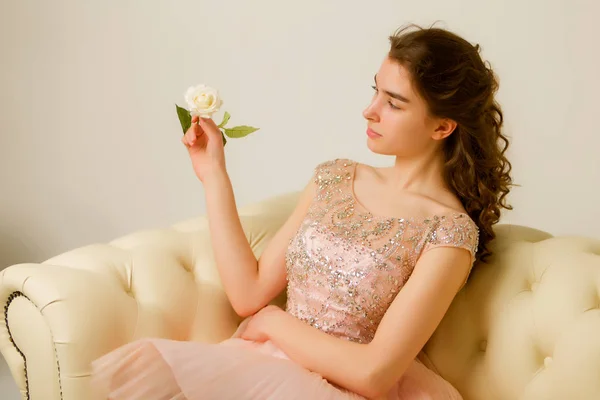 Teenie-Mädchen sitzt auf dem Sofa und hält eine Blume in der Hand. — Stockfoto