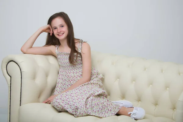 Hermosa joven sentada en el sofá junto a la chimenea —  Fotos de Stock