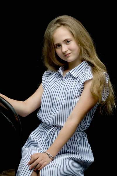 Очаровательная девочка-подросток, сидящая на стуле в студии на бла — стоковое фото