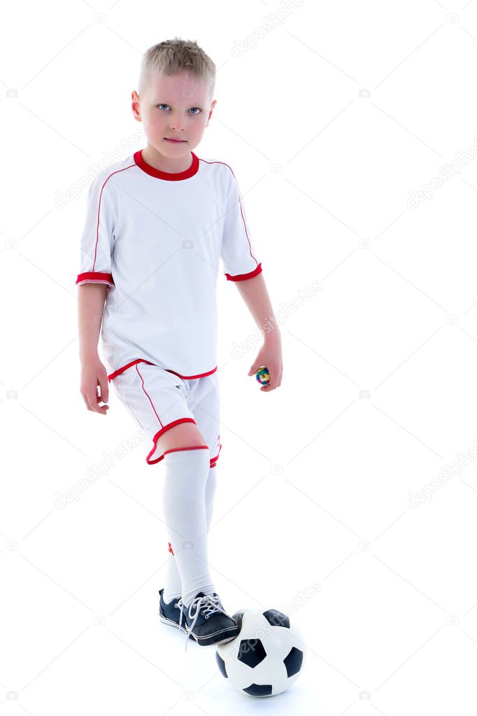 A little boy wearing a pure white t-shirt is playing with a socc