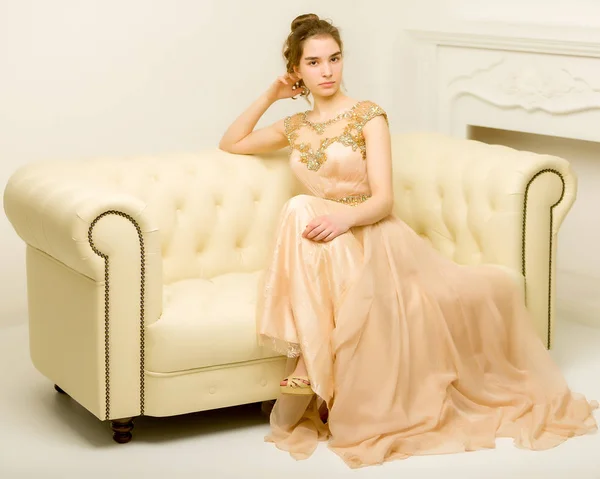 Menina adolescente em vestido elegante sentado no sofá . — Fotografia de Stock