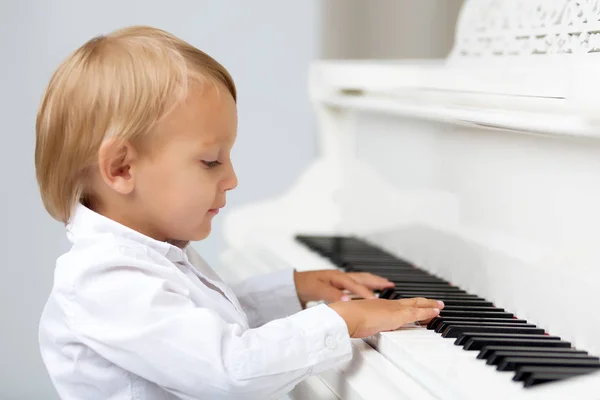 Mały chłopiec w studio w pobliżu biały fortepian. — Zdjęcie stockowe