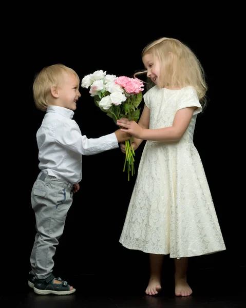 Een jongetje geeft een meisje een boeket bloemen. Het concept van l — Stockfoto