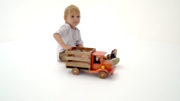 Pequeño niño está jugando con un coche de madera . — Vídeos de Stock