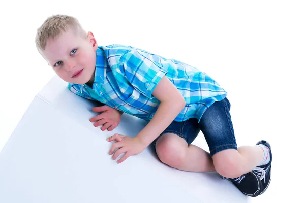 Un beau petit garçon est photographié près d'un cube blanc. Le co — Photo