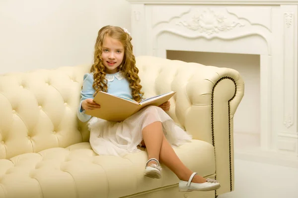 Liten flicka sitter på soffan — Stockfoto