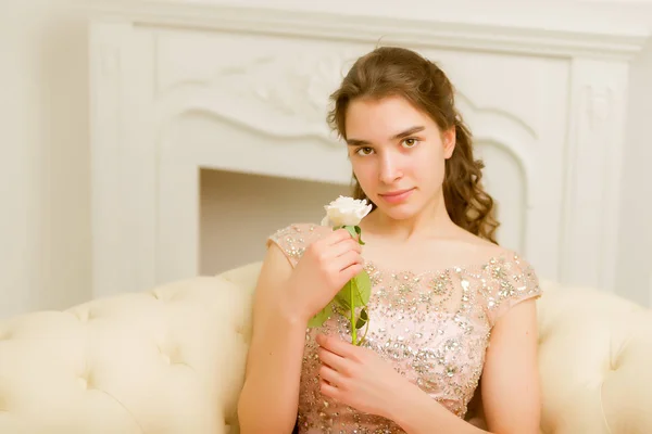 Teenie-Mädchen sitzt auf dem Sofa und hält eine Blume in der Hand. — Stockfoto