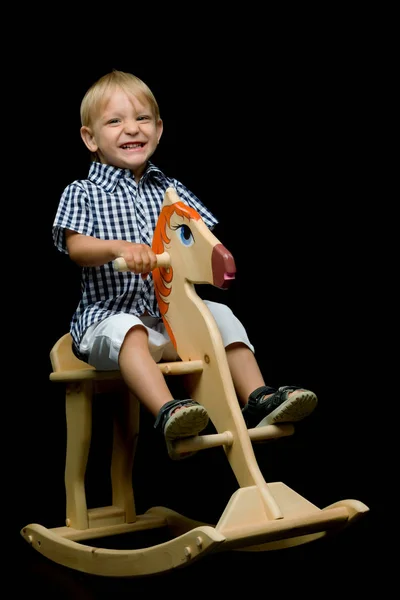 Un ragazzino sta cavalcando un cavallo di legno — Foto Stock