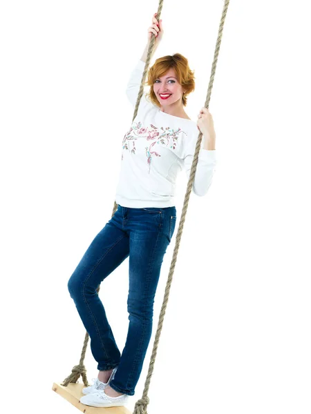 Beautiful young woman on a swing against white studio backgroun — Stock Photo, Image