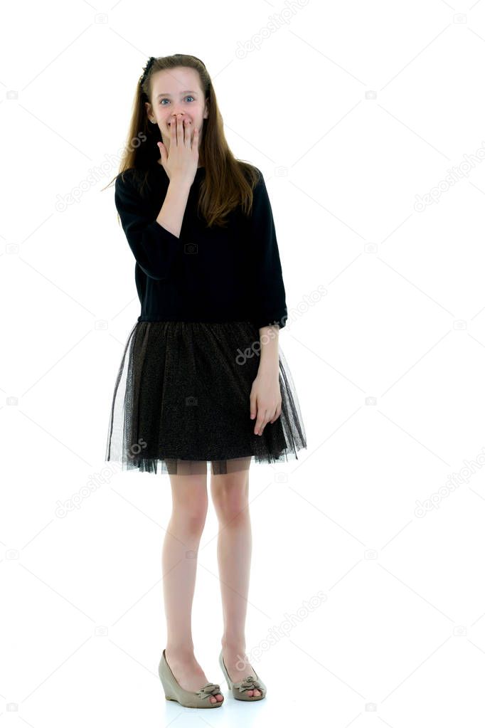 Portrait of a cute little girl covering her mouth with hands, is