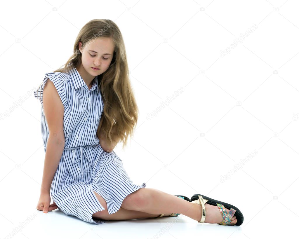 Teen girl posing on the floor in the studio. The concept of styl
