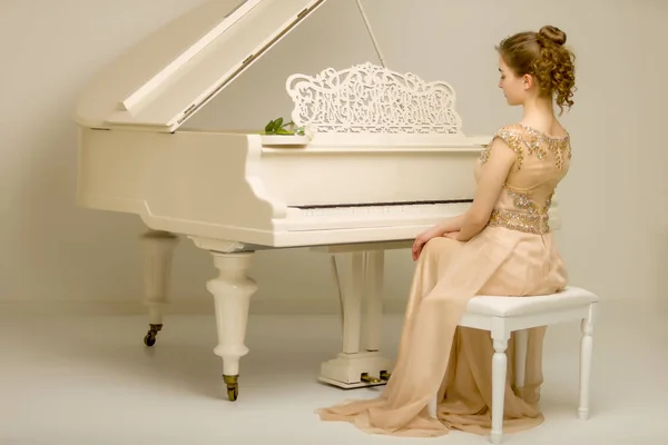A menina está no piano de cauda branco. — Fotografia de Stock