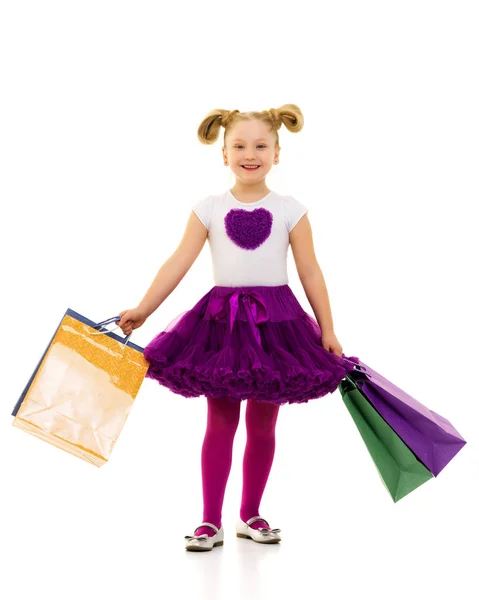 अपने हाथों में बहु रंगीन बैग के साथ छोटी लड़की . — स्टॉक फ़ोटो, इमेज