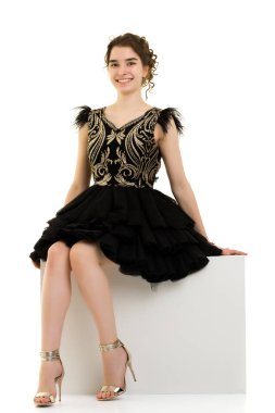 Genç kız beyaz bir küp üzerinde stüdyo poz.