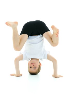 Küçük bir çocuk başının üstünde duruyor. Bir spor egzersizi yapar