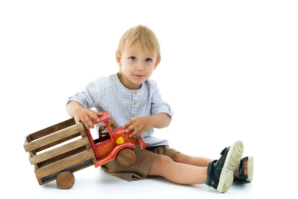 Pequeño niño está jugando con un coche de madera . —  Fotos de Stock