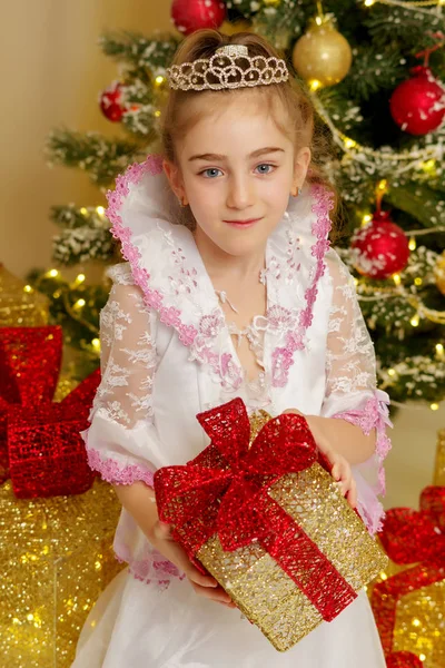 Bambina vicino all'albero di Natale con un regalo. — Foto Stock