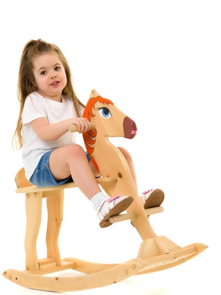 Menina balançando em um cavalo de madeira . — Fotografia de Stock