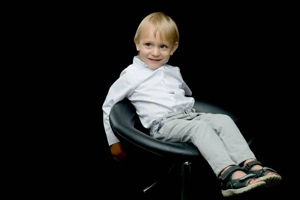 Симпатичный маленький мальчик сидит на стуле. — стоковое фото
